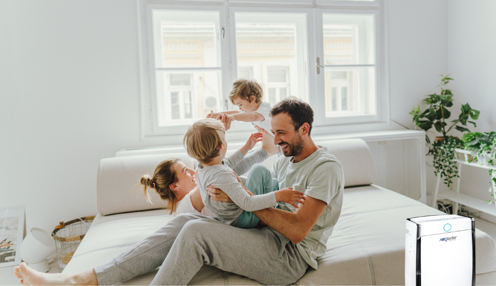 father with 3 children playing happily besides AirDoctor 3000